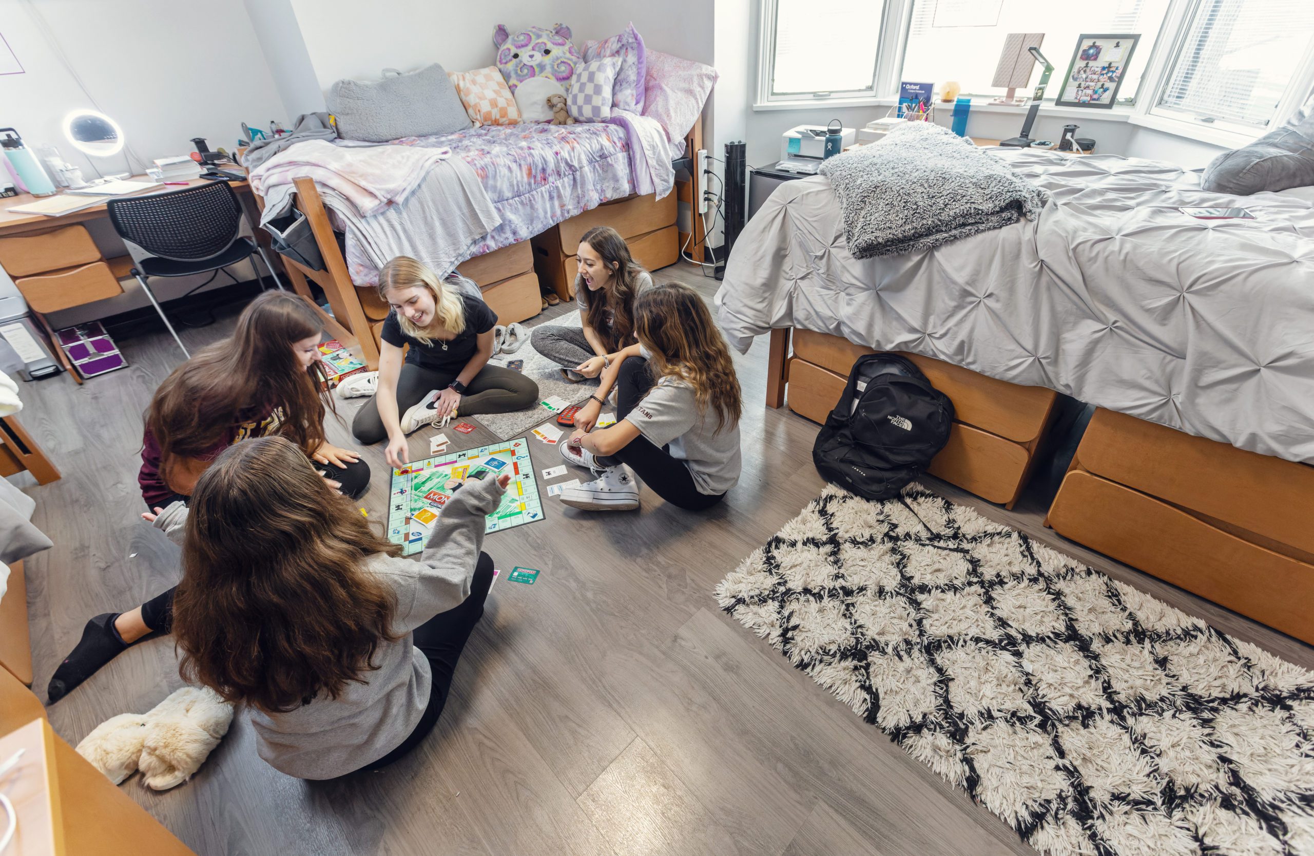 group of females sitting on dorm room floor playing game