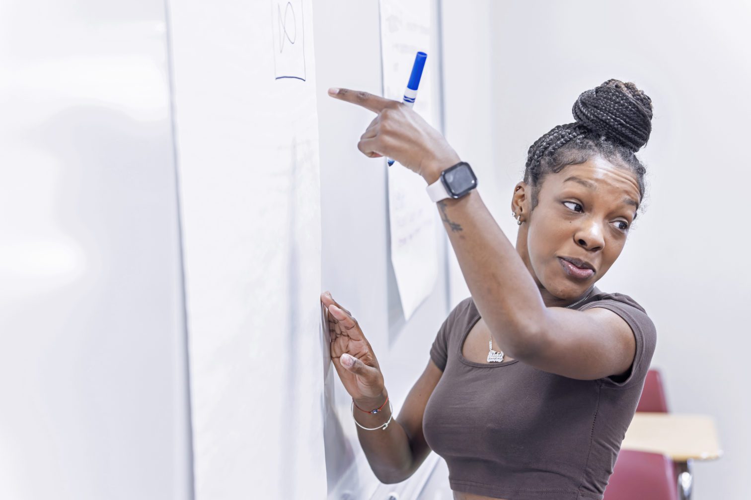 A female student writing on a paper hang on the wall.