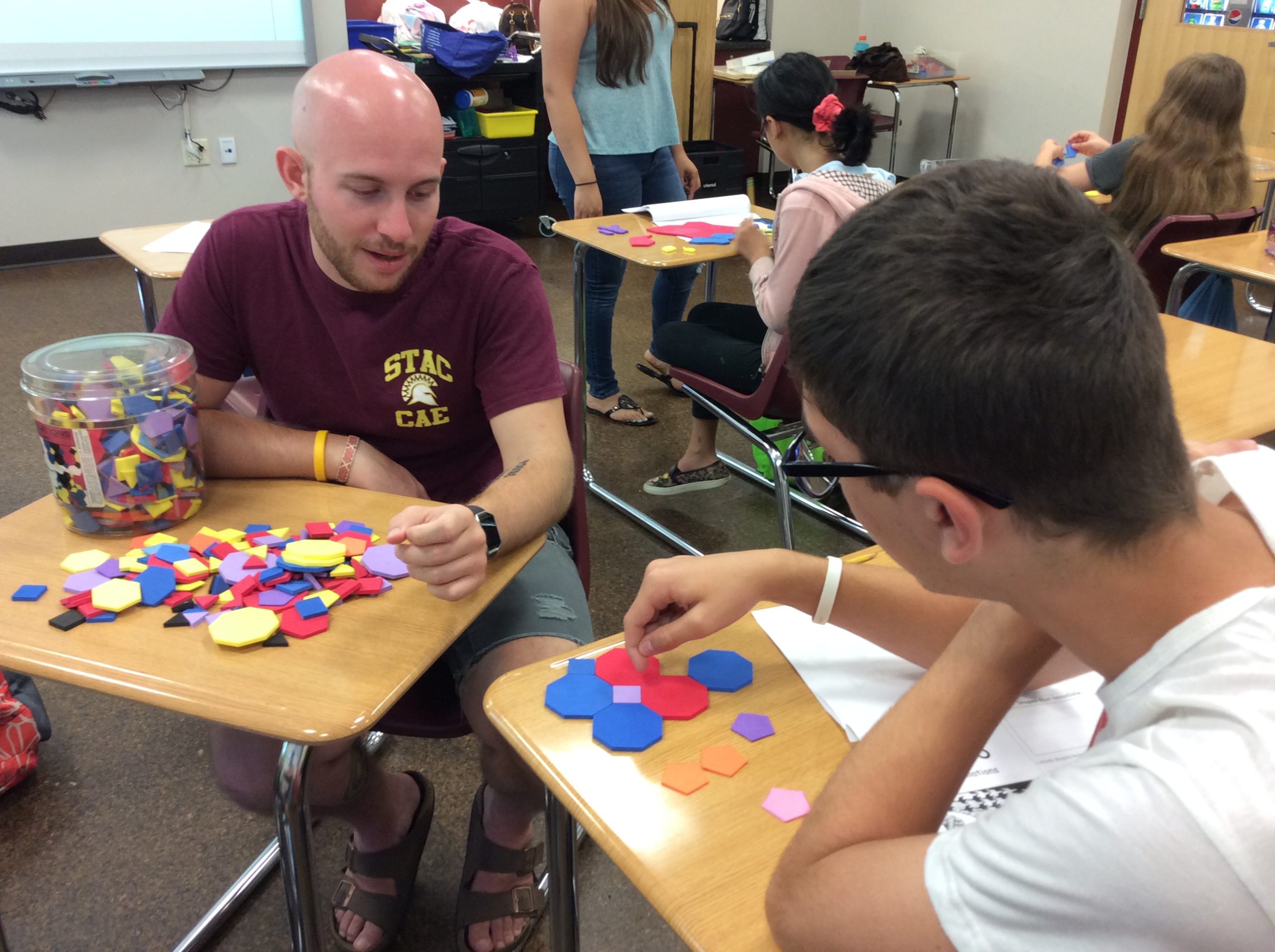 Students and children working with cutout shapes of different colors.