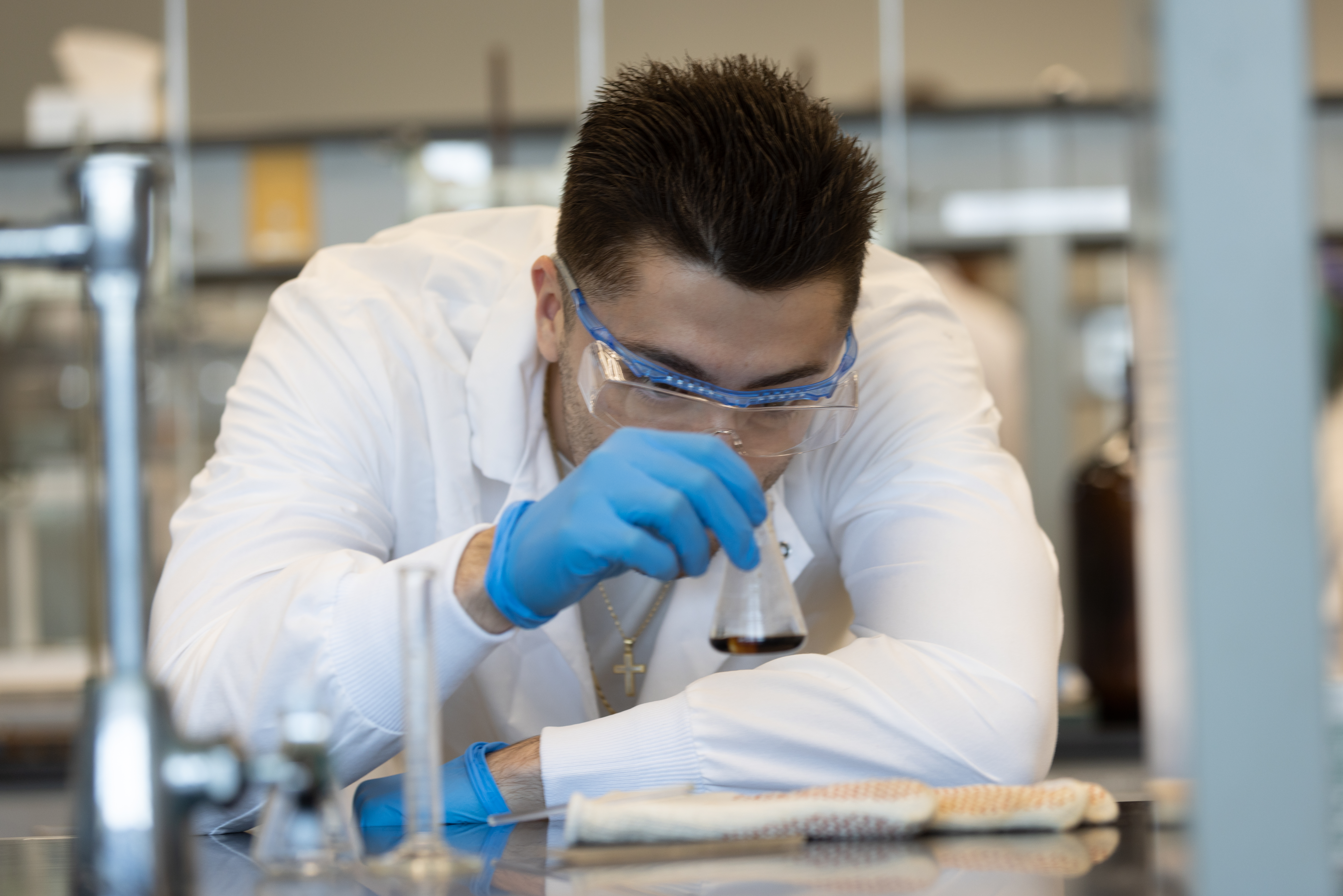 A male student holding a flask in the lab.