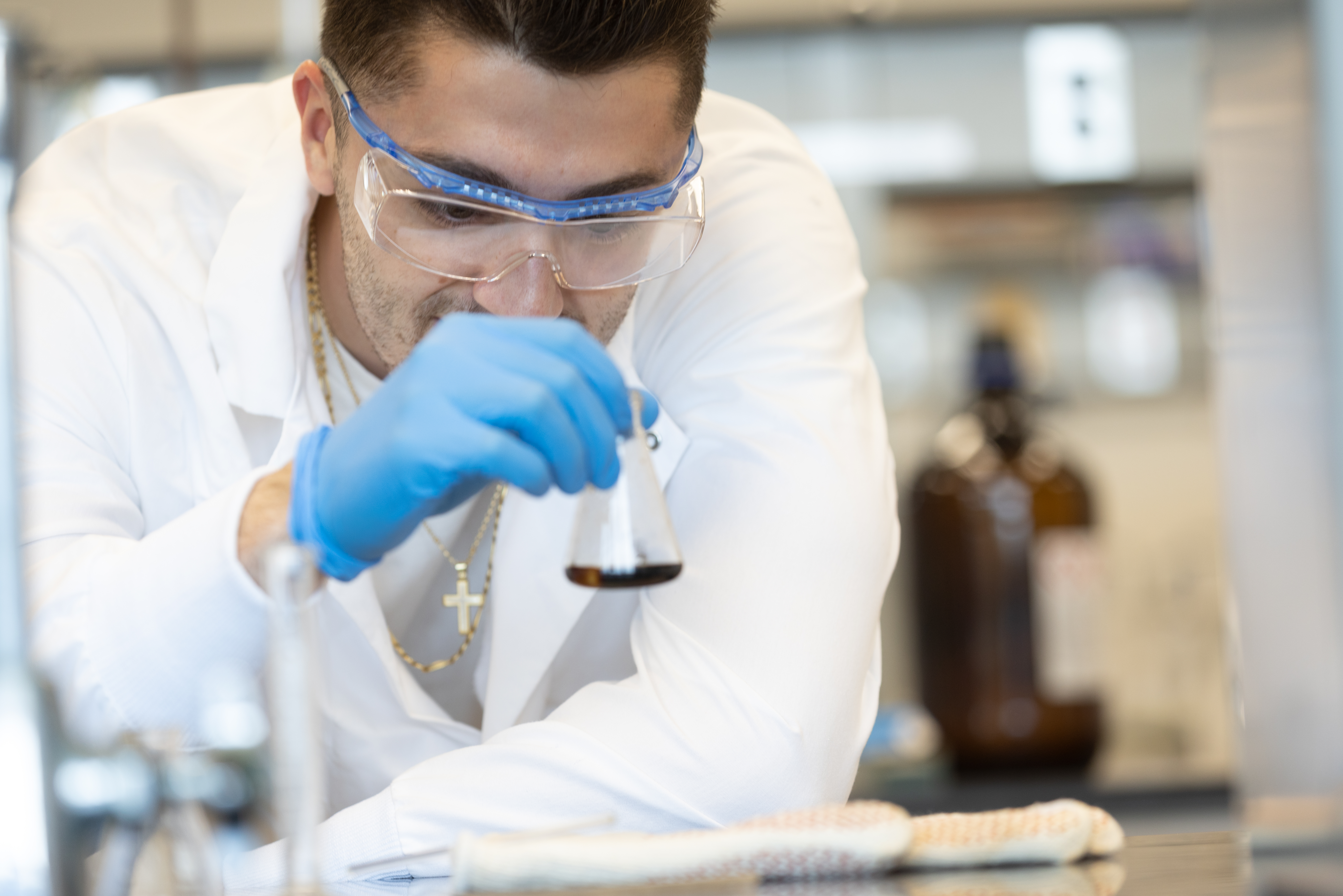 A male student in the chemistry lab holding a flask.
