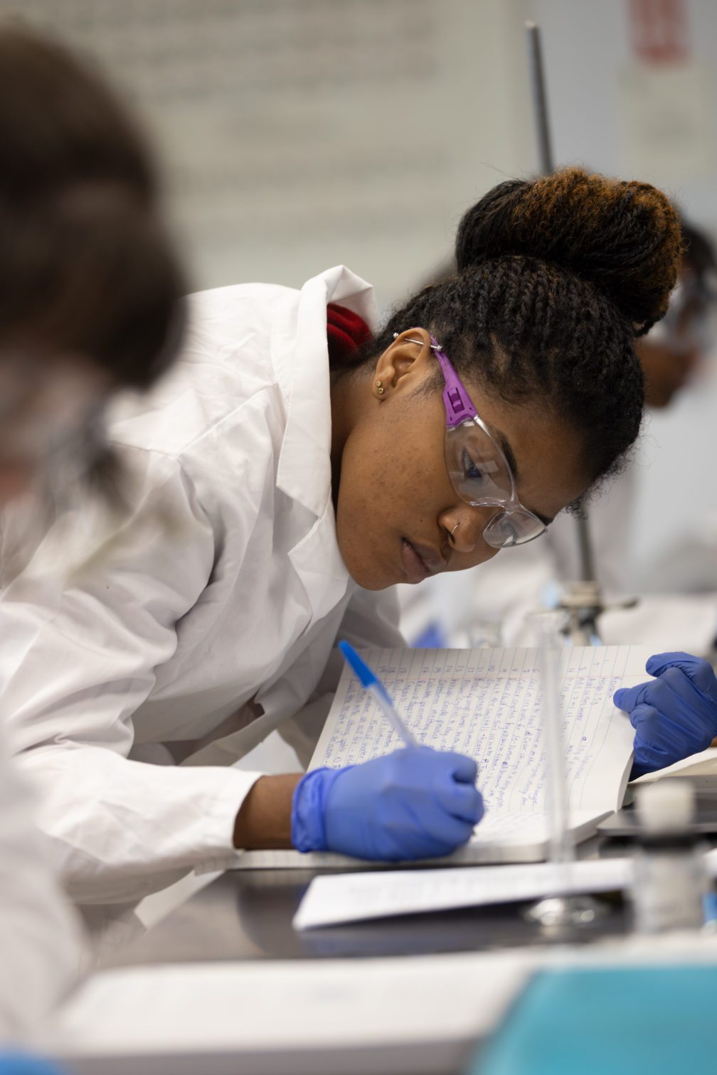 A female student in the lab writing in a notebook.