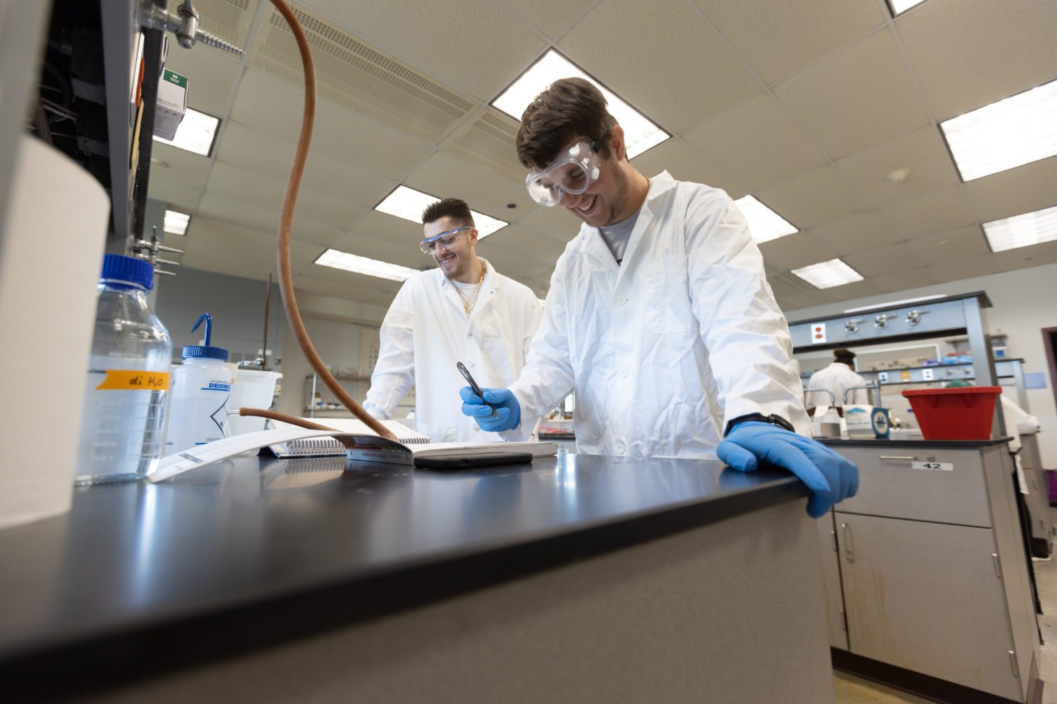 Students in the Biology lab working on experiments and writing in a notebook.