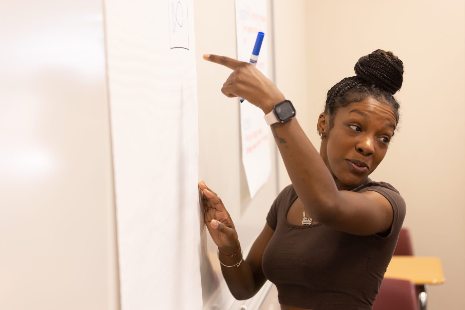 A female student writing on a paper hung on a wall.