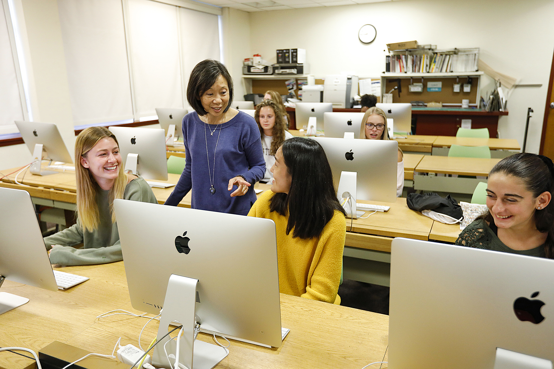 Female students and their professor working on computers.