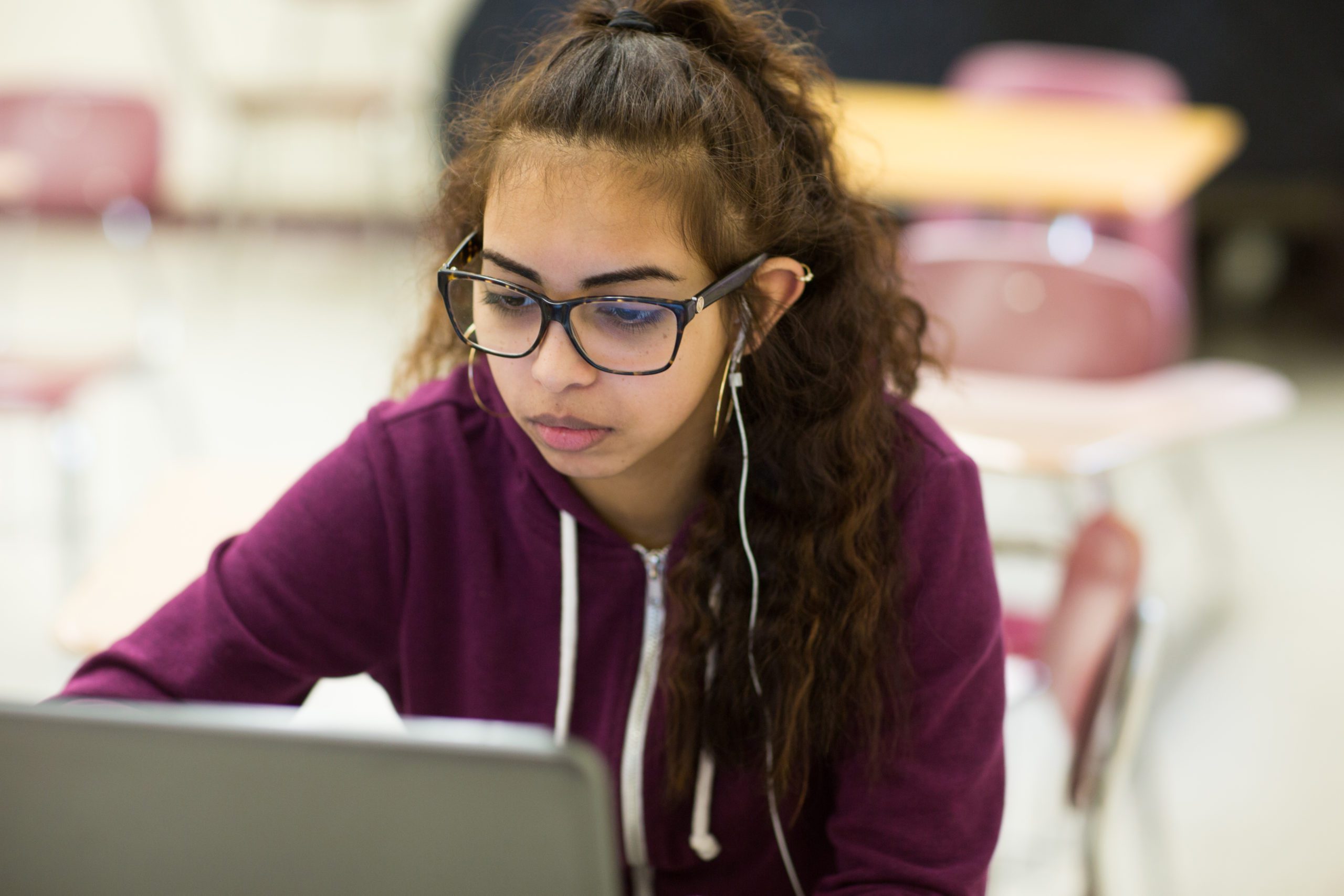 A female student with glasses working on a computer.