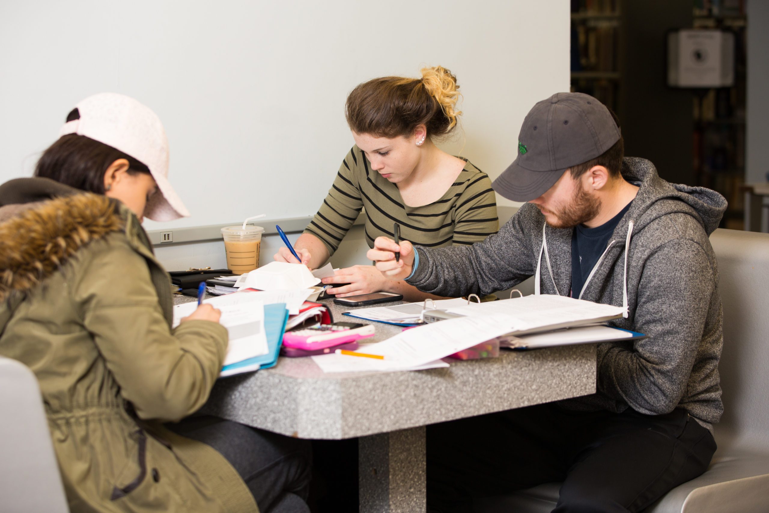 Students sitting at a table and studying in the library.
