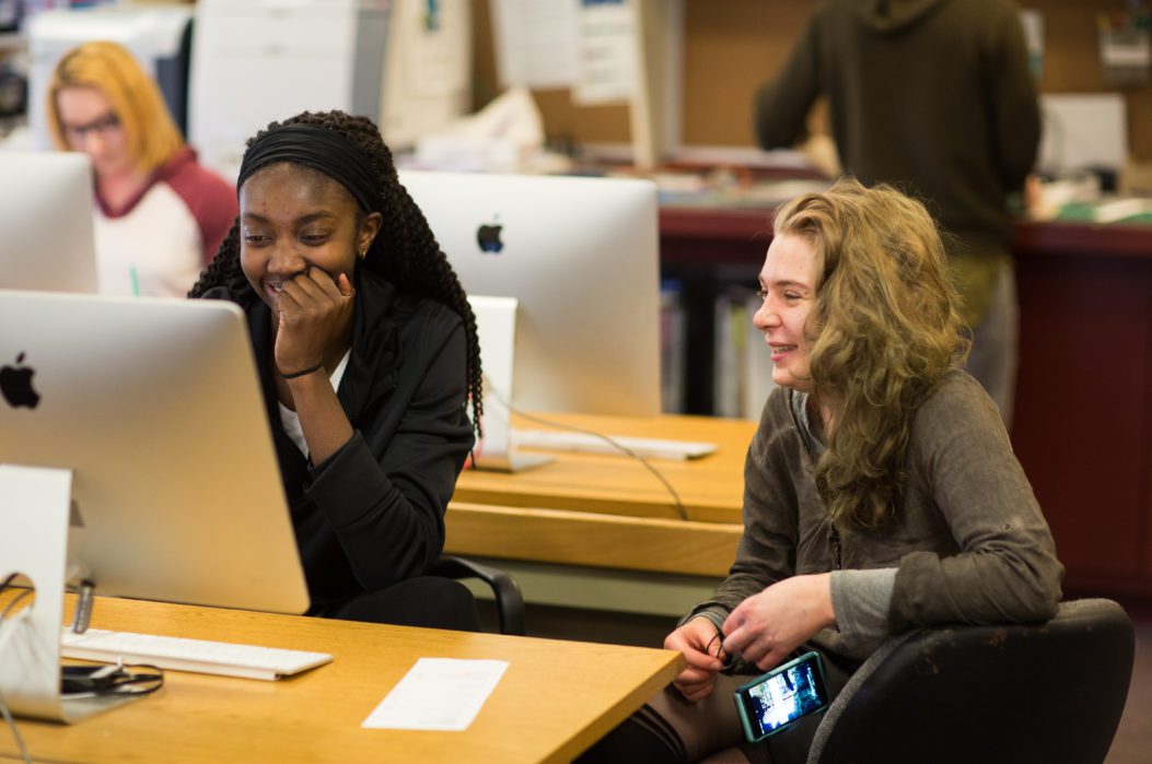 Students sitting at a table in front of a computer in the Maclab.