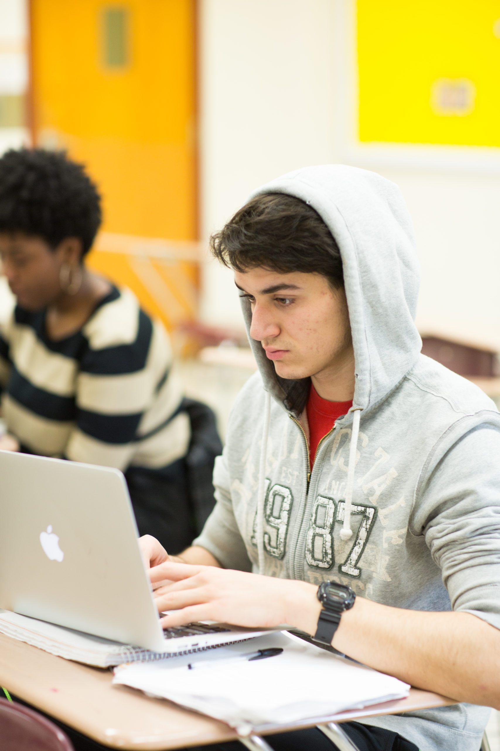 students sitting at a desk in a classroom studying.