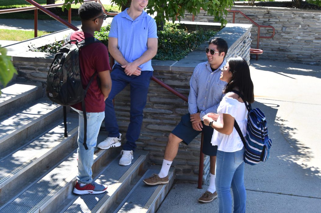 Four students standing on the stairs outside.