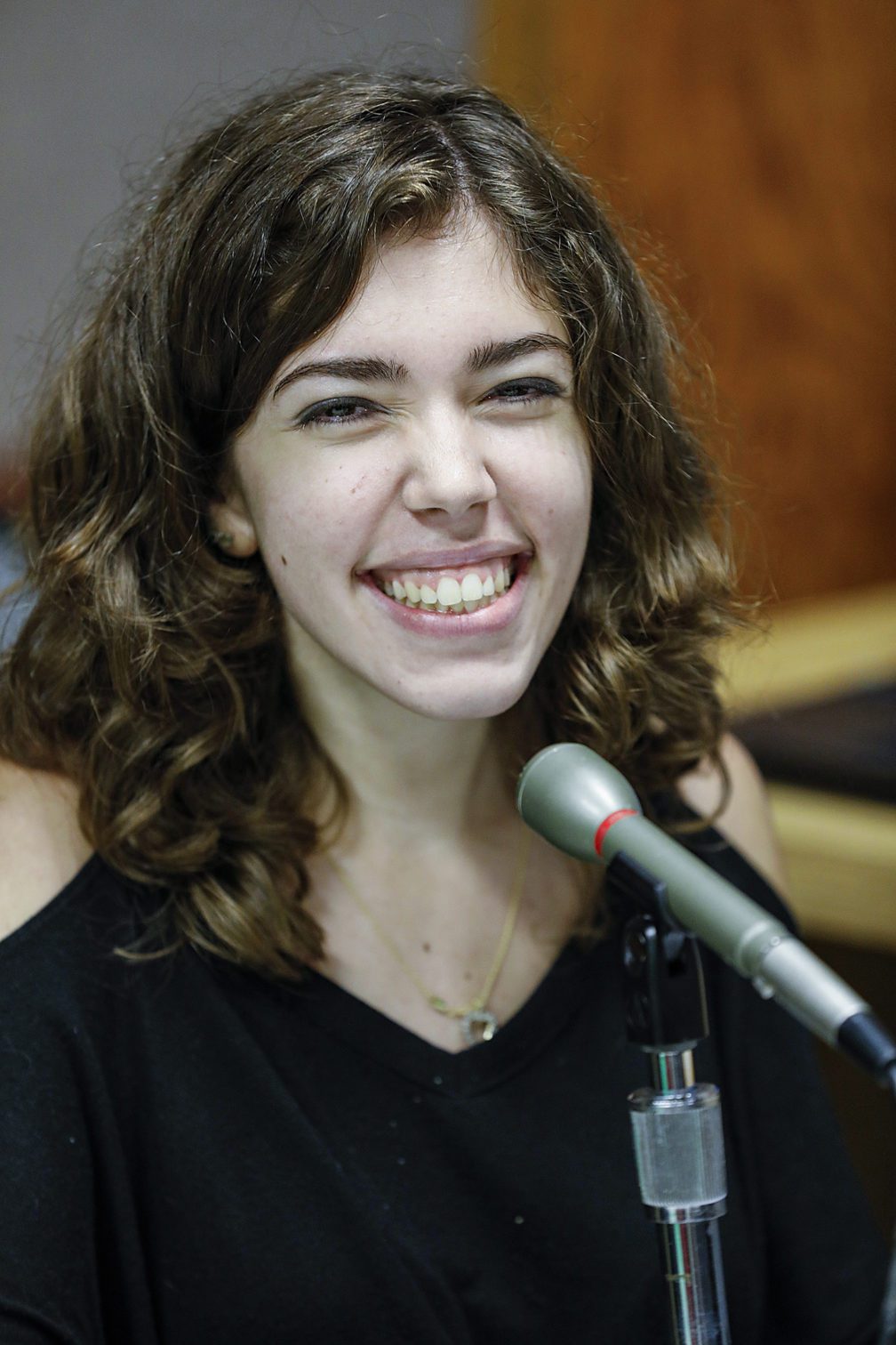 A female student sitting at a desk with a mike in front of her.