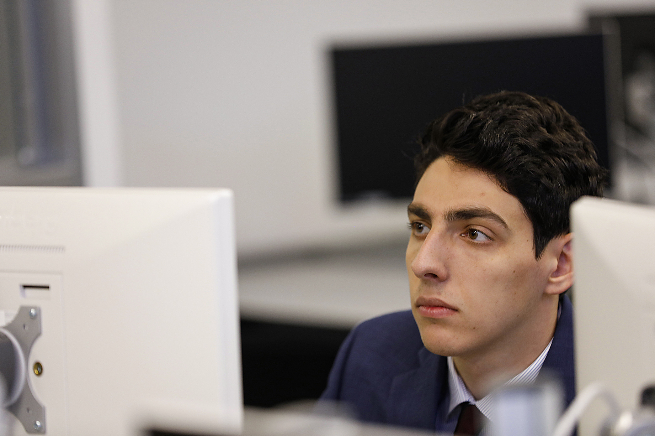 A male student sitting at a desk in front of a computer.