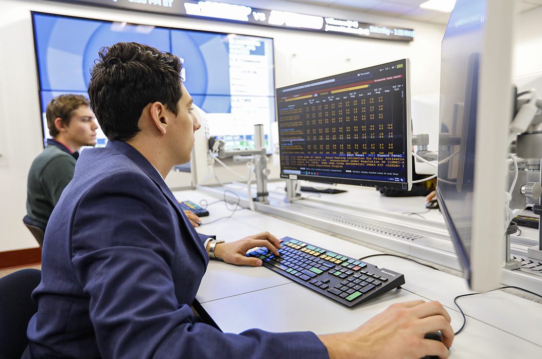 Two male students sitting at desks in the Bloomberg lab working on computers.