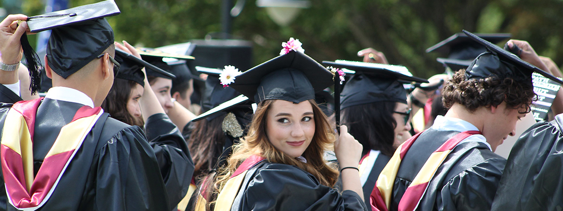 student smiling holding tassel at graduation