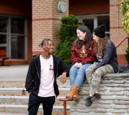 Three STAC students talking in front of Aquinas Hall