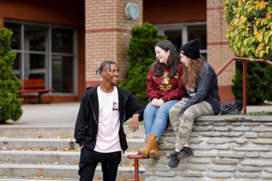 Three STAC students talking in front of Aquinas Hall