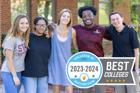 5 students standing arm in arm smiling outside of Borelli Hall