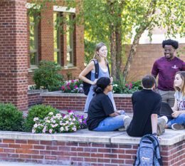 5 students outside of Borelli Hall on campus chatting