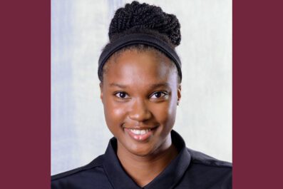 Chanelle smiling wearing black STAC Triathlon shirt with hair in a bun and white and maroon background