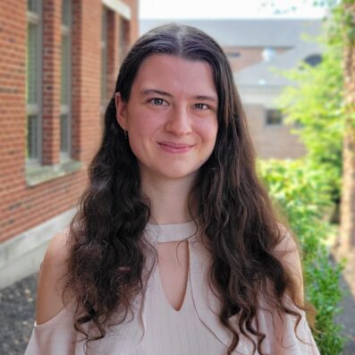 Alexandria Porter smiling with Borelli Hall building, trees, and greenery in background