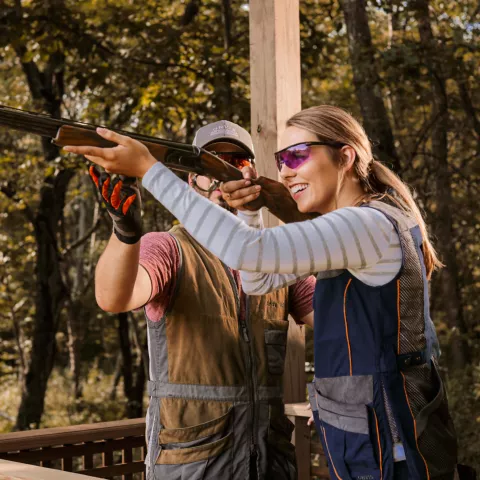 Man helping women use a skeet shooting Gun