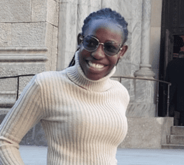 Cindy smiling outside wearing glasses and white sweater