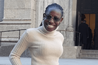 Cindy smiling outside wearing glasses and white sweater