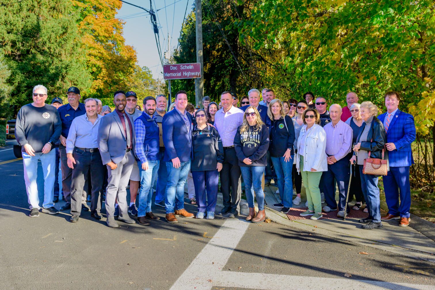 Group of Friends standing next to the Doc Schelin Memorial Highway Sign