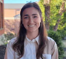 Sarah smiling with green trees and Borelli Hall and Romano buildings in background