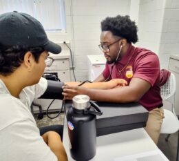 Two students in exercise science lab performing health assessments and blood pressure test