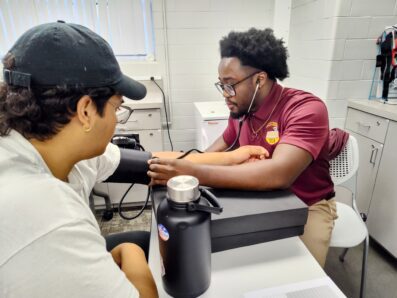 Two students in exercise science lab performing health assessments and blood pressure test