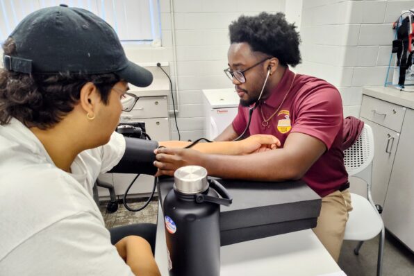 Two students in exercise science lab performing health assessments and blood pressure test